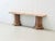 The piece of furniture shown is a striking console table made of reddish-brown marble with vibrant veining and a polished...