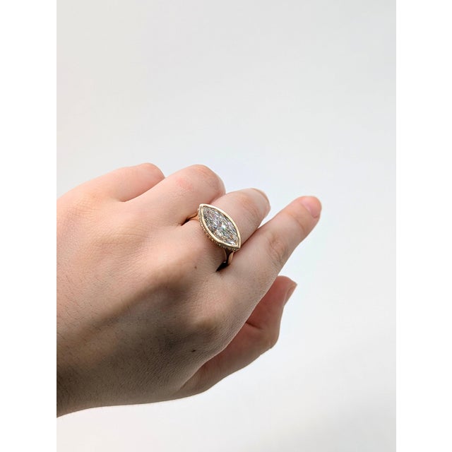 A striking marquise lab grown diamond stretches elegantly across this ring, lined with sparkling lab grown diamond accents...