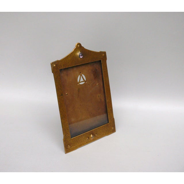 A unique Art Nouveau picture frame made of brass, adorned with a glass carbouchon. Its design is reminiscent of works from...