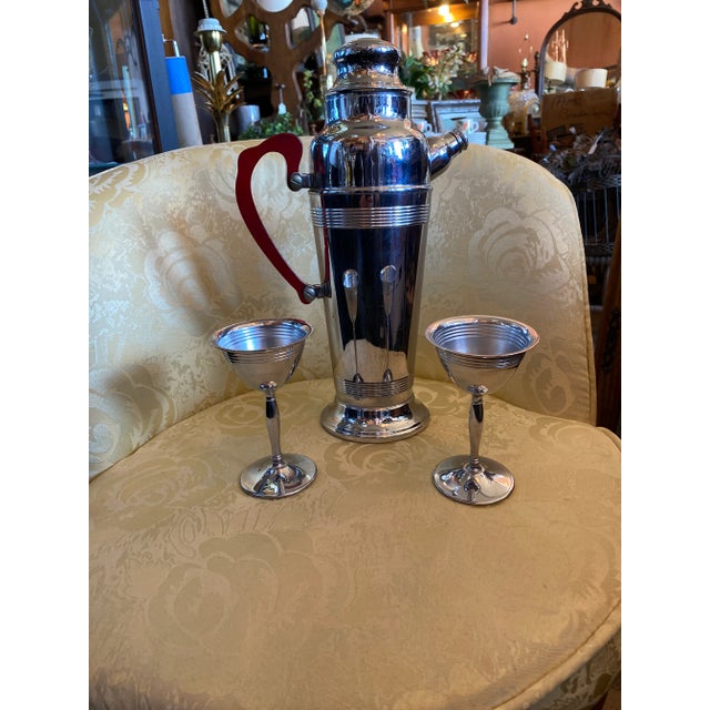 Mid Century Modern Chrome and Stainless Shaker Set with Two Goblets . The Pitcher has a Red Bakelite Handle .