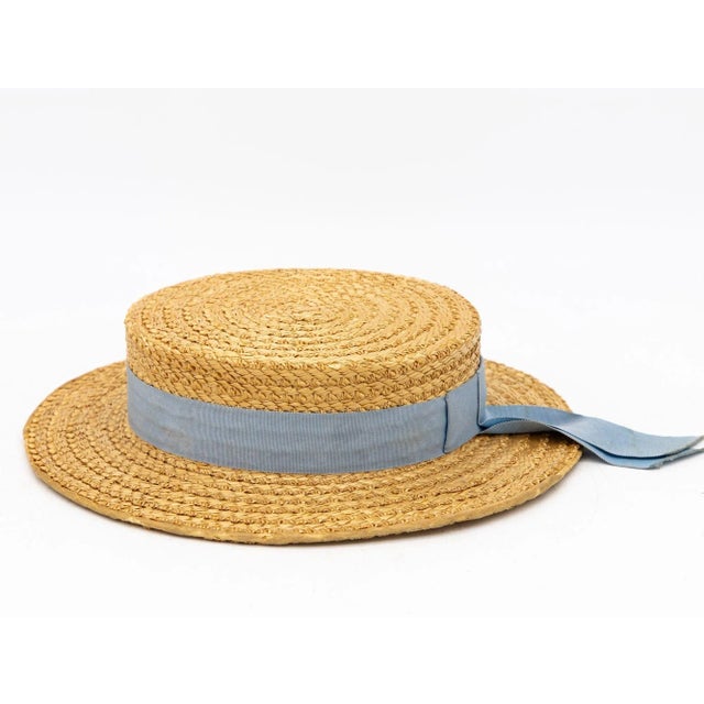 The Ridgemont Make's vintage 1930s boater hat showcases timeless elegance with its natural straw construction. Adorned...