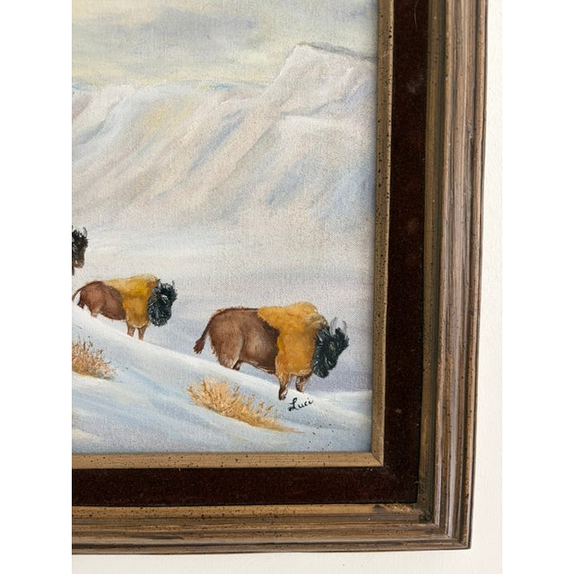 Vintage oil on canvas painting depicting a group of bison moving across a snow-covered landscape. The scene has a calm,...