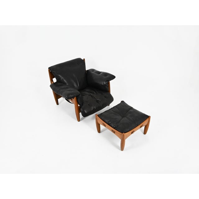 Armchair with ottoman in black leather and wood by sergio rodrigues. Model: sheriff. Stamped isa. Seat height: 37 cm....