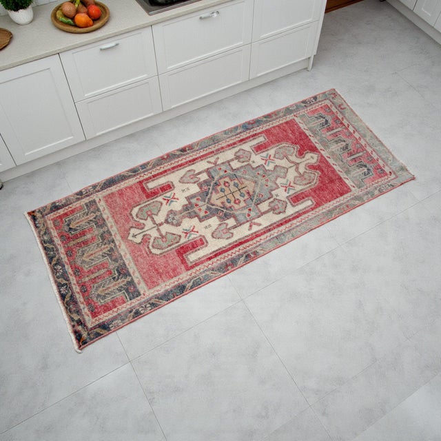 This vintage Oushak rug features a captivating geometric medallion surrounded by a sun-faded red and soft cream palette....