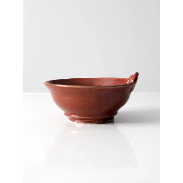This vintage studio pottery bowl features a hand-crafted form accented by a distinctive crested swirl design. A rich...