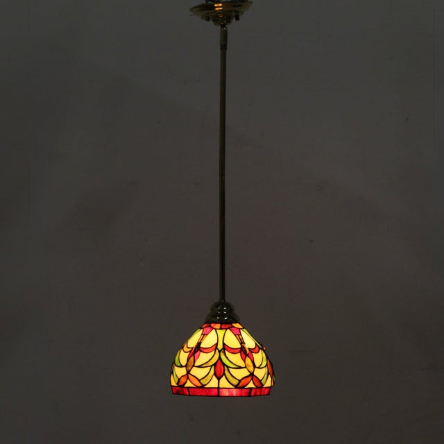 Tiffany style mini pendant single-light fixture showcases a vibrant dome shade with individual pieces of slag glass...