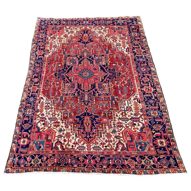 A beautiful antique Heriz carpet, handwoven circa 1920 with a large geometrical medallion on a terracotta field and deep...
