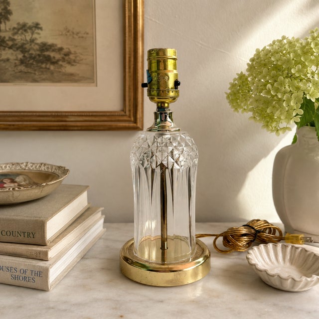 Elegant vintage accent lamp featuring a faceted clear pressed-glass body paired with a brass-tone metal base. Its timeless...