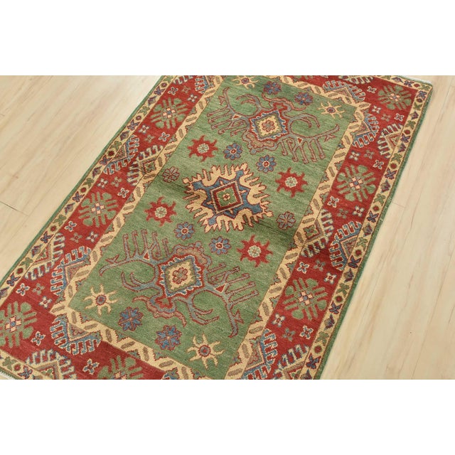 A tribal Caucasian Kazak rug hand-knotted with an all-wool pile on a cotton foundation. This oriental rug features...