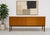 Long Mid Century Modern teak credenza sideboard featuring striking wood grains and a thoughtful layout. This elegant piece...