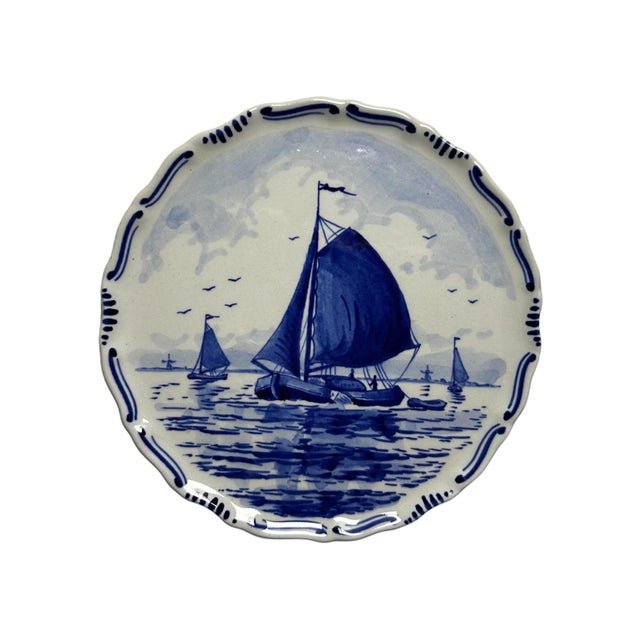 A pair of small hand-painted royal delft plates by de porceleyne fles, made in 1982 and 1983. Each plate has a scalloped...