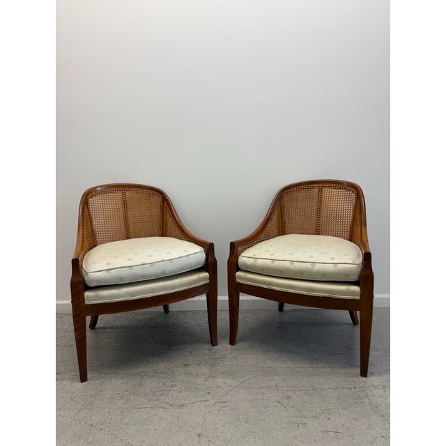An elegant pair of Baker Furniture barrel lounge chairs crafted from richly finished walnut with beautifully handwoven...