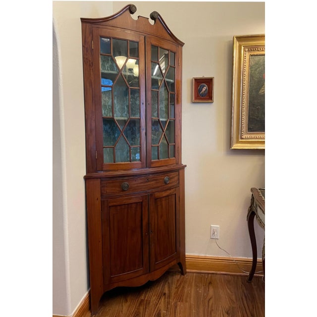 Edwardian Mahogany Corner Cabinet. This English mahogany cabinet is an elegant corner piece. The cupboard top is ornately...