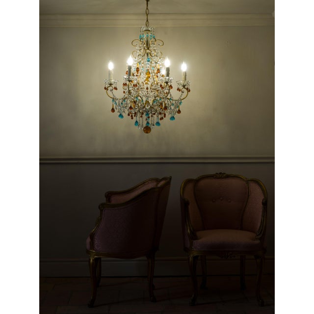 Florentine chandelier from the 1960s in gilded metal with crystals and colored Murano glass pendants. The structure is...