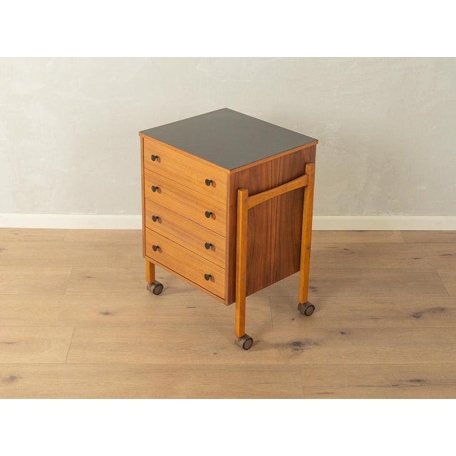 Beautiful chest of drawers from the 1960s. The body is finished in walnut veneer with four drawers and casters. The top is...