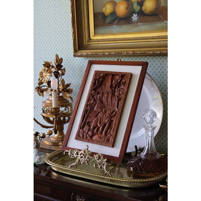 A beautifully detailed vintage Southeast Asian teak bas-relief depicting an elephant within a richly layered architectural...