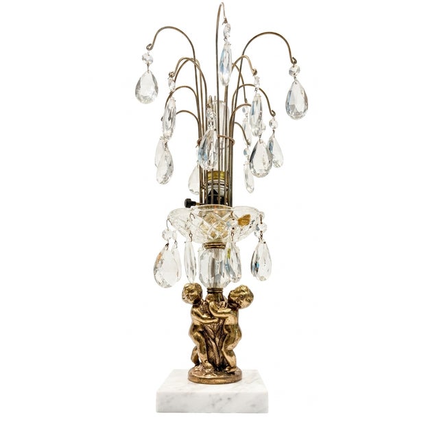 Featuring intricately detailed brass-finish cherubs cascading beneath a shimmering waterfall of glass prisms, this piece...