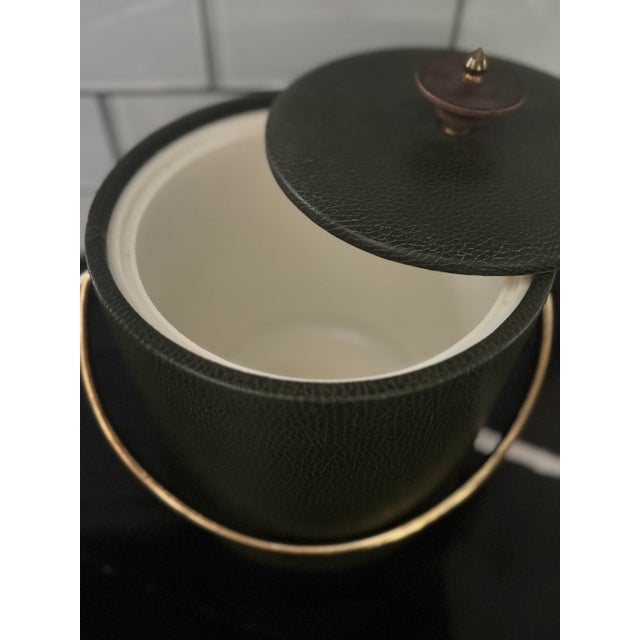 Vintage mid-century faux leather ice bucket in deep green with brass handle and finial lid. A stylish barware accent with...