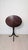 A charming English tilt-top tea table featuring an elegant oval tabletop, turned pedestal column, and gracefully curved...