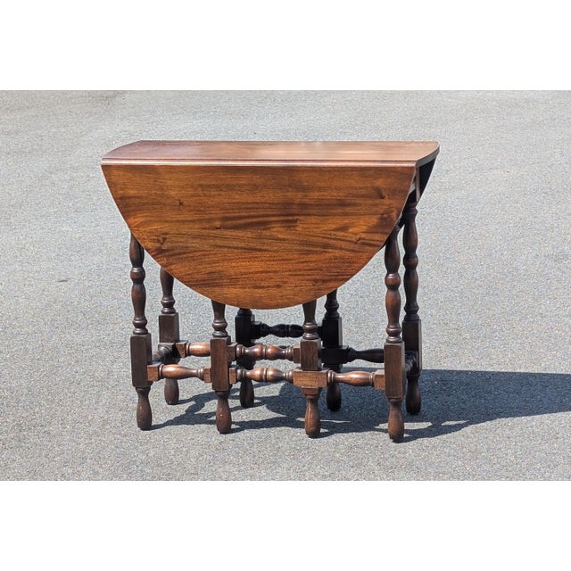This vintage English William and Mary style gateleg table is a masterpiece of traditional craftsmanship, featuring a rich...
