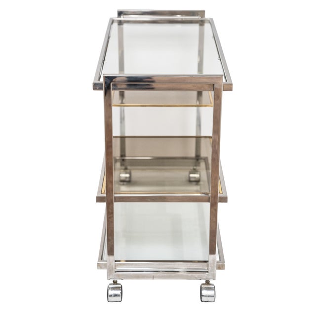 A fine Italian Modern drinks cart or bar trolley featuring an elegant three-tier rectangular frame of chrome and brass....