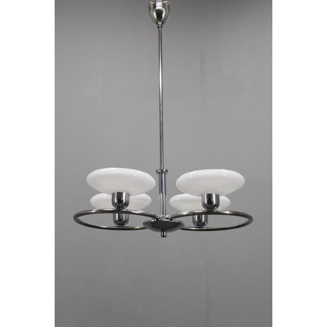 Elegant mid-century chrome chandelier produced in 1950s czechoslovakia, distinguished by its four large milk-glass disc...