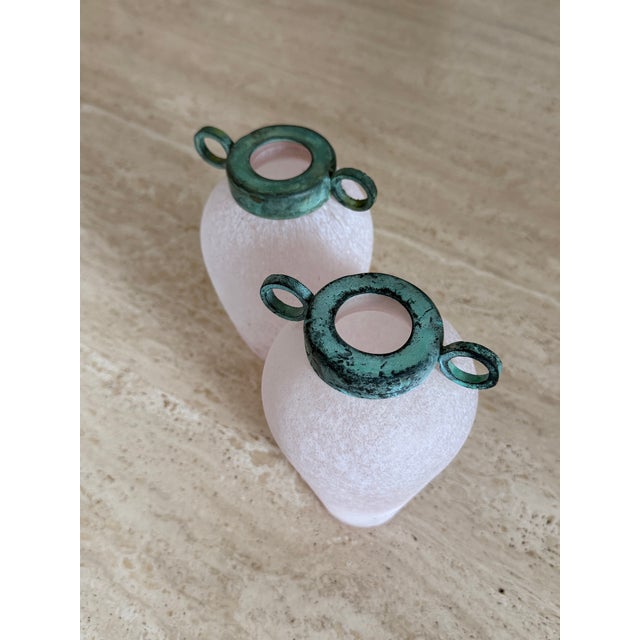 A set of two glass bud vases with verdigris metal caps. These 1980s pieces are designed to be displayed as a set; they...