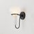 A delicate metal framework supports the upside-down, pear-shaped shade of the Adams Corner sconce. Adding a surprising...