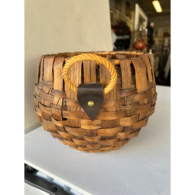 The vintage basket features rounded woven body. The basket is equipped with a rope handle attached by leather tabs and...