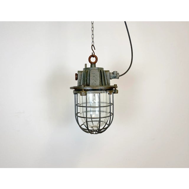 Industrial hanging lamp made in former Czechoslovakia during the 1960s. It features cast iron top, clear glass cover and...