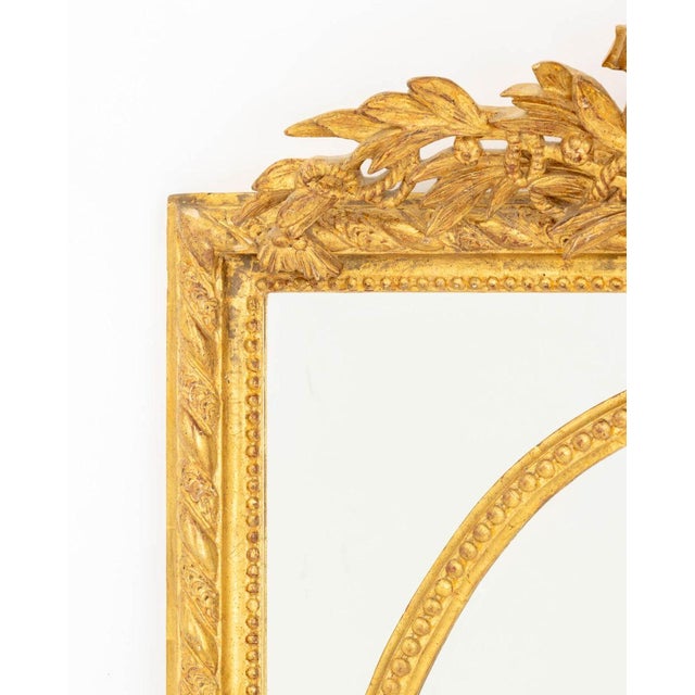 Louis XVI Style Giltwood Framed Cushion Mirror, with foliate motif crest and beveled glass. Overall: 50" H x 35.5" W x...