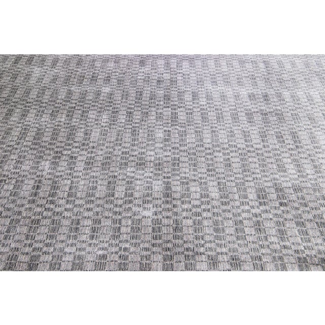 Meticulously crafted by hand using a blend of silk and wool, this exquisite contemporary rug showcases a stunning gray...