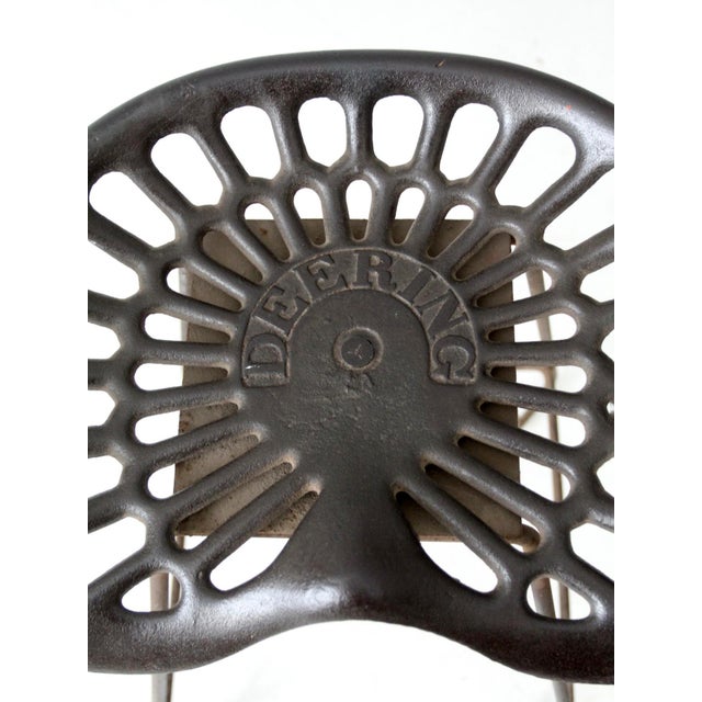 An original late 19th-century Deering cast iron tractor seat lends this vintage iron stool its unmistakable character. The...