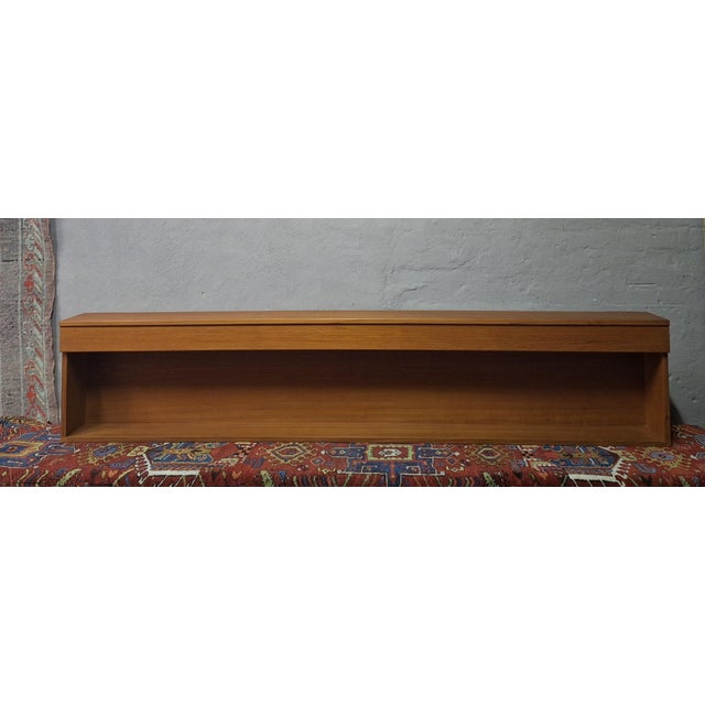 Danish long teak floating sideboard / shelf dating from about 1960, finely-shaped teak casing enclosing shelf, with two...