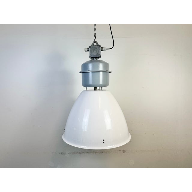 This industrial pendant light was made by elektrosvit in slovakia during the 1990s. It features a white enamel shade and...