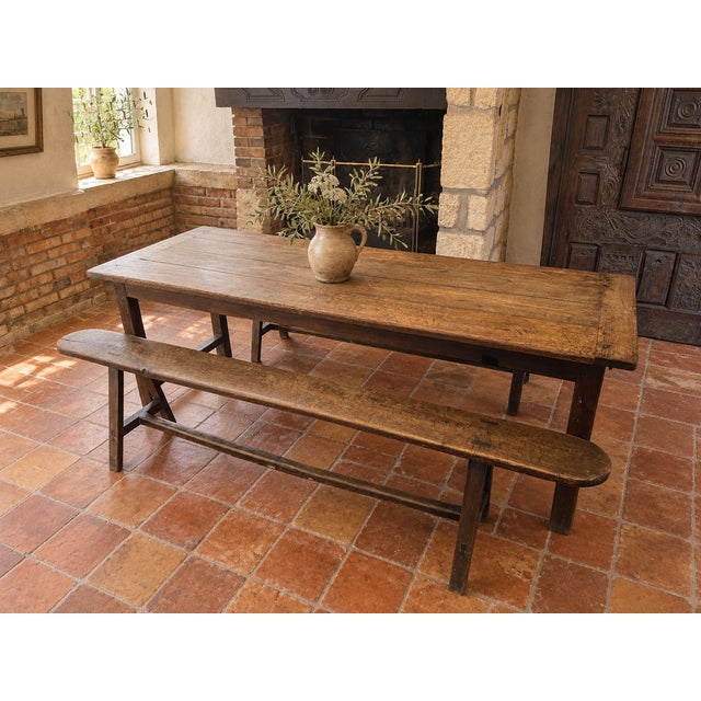Antique French dining set comprising a large solid oak farmhouse table and two matching long benches, likely dating from...