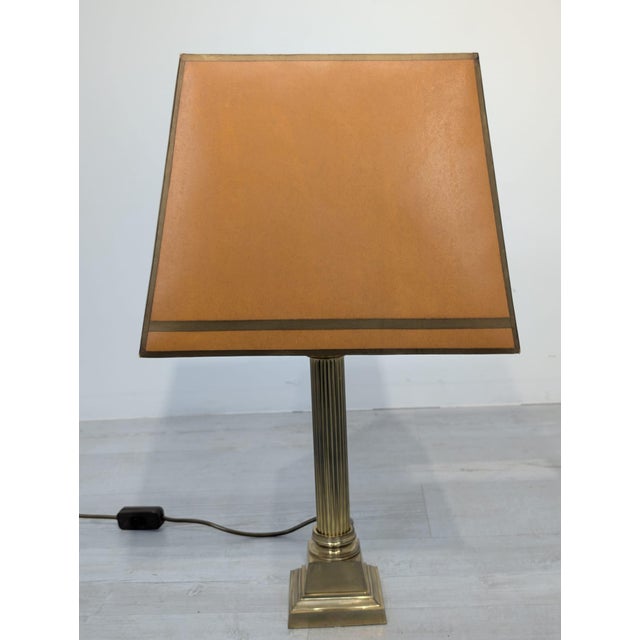 Stylish brass table lamp from the 1970s. The base is brass-colored and the shade is a warm, golden hue. The lamp has a...