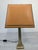 Stylish brass table lamp from the 1970s. The base is brass-colored and the shade is a warm, golden hue. The lamp has a...