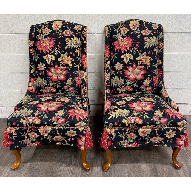 This is an elegant vintage pair of Queen Anne style wingback lounge chairs featuring graceful pad feet, turned stretchers,...