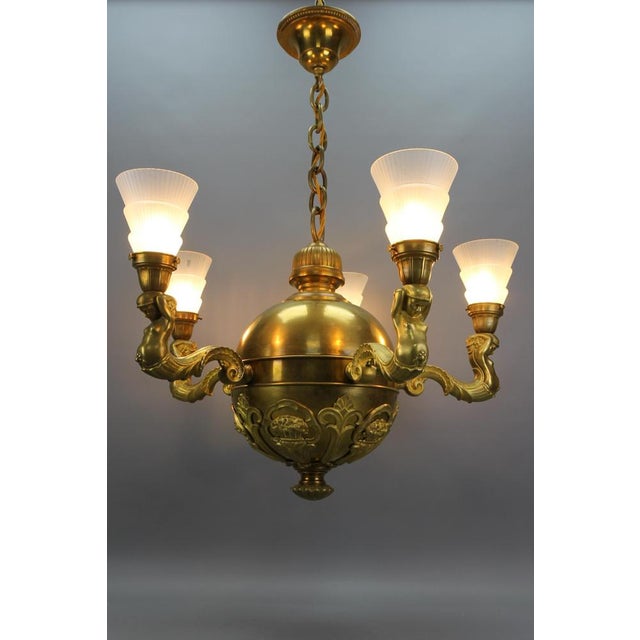 Art Deco brass, bronze, and frosted glass five-light figural chandelier from ca. 1920, Germany. This impressive Art Deco...