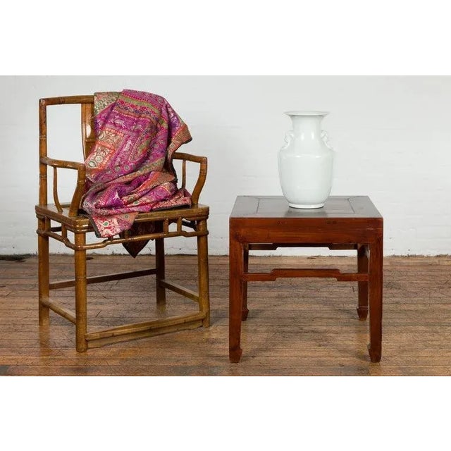 A Chinese Qing Dynasty period side table from the 19th century, with dark brown finish, humpbacked stretcher and horse...