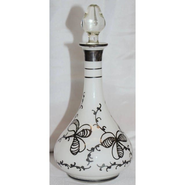 Three leaf clovers in silver surround this lovely bottle made of clear over opal cased glass. It is topped with a clear...