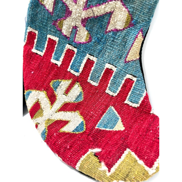 Pair of vintage Turkish kilim Christmas stockings handmade from richly patterned wool rug textiles in saturated red, blue,...