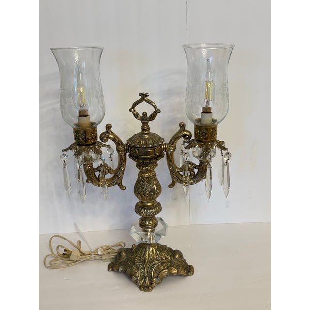 The design of this double-armed Hollywood Regency candelabra crystal table lamp is from the mid-20th century, around the...