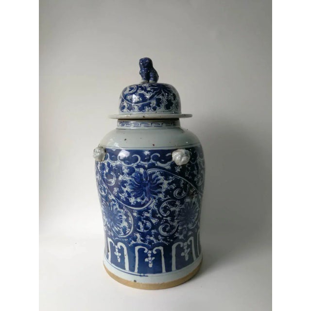 This blue and white porcelain jar is adorned with hand painted flowers and vines. The lid has a small foo dog on top....
