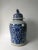 This blue and white porcelain jar is adorned with hand painted flowers and vines. The lid has a small foo dog on top....