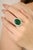 This luxurious cocktail ring showcases a certified 13.17 ct oval-cut emerald, surrounded by a 3.39 ct sparkling halo of...