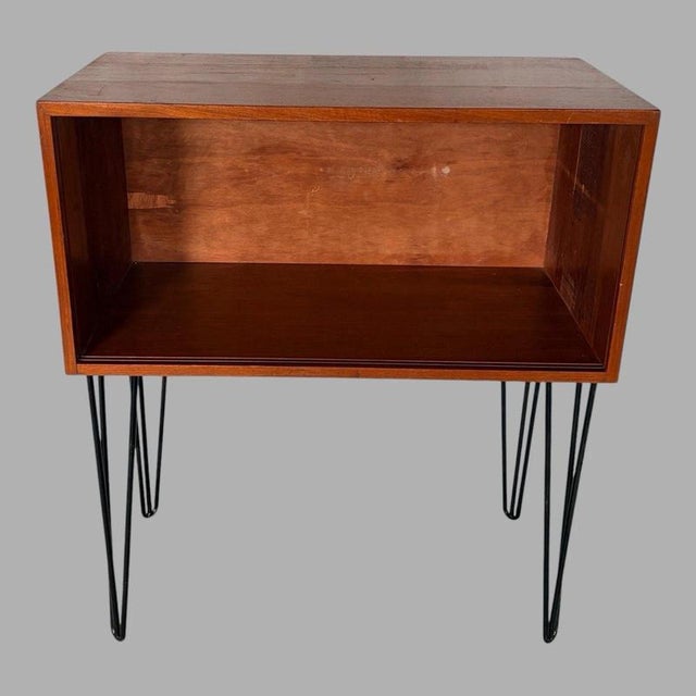 A compact and versatile mid-century teak open cabinet, raised on slender black metal hairpin legs for a clean,...