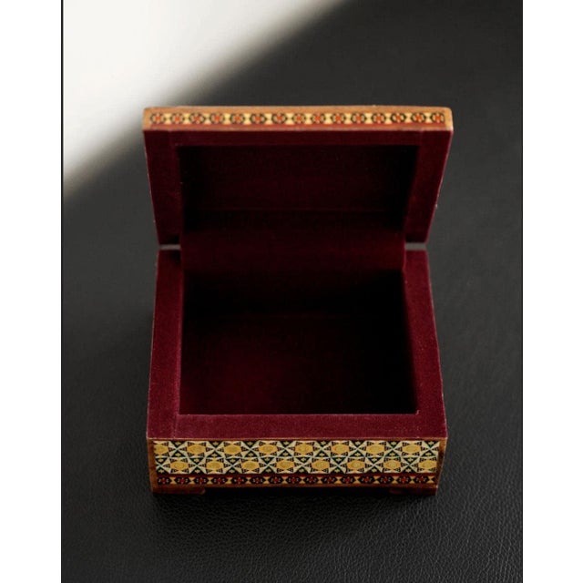 A compact wooden jewelry box with a hand-painted garden composition of birds and flowers on a turquoise ground. Geometric...