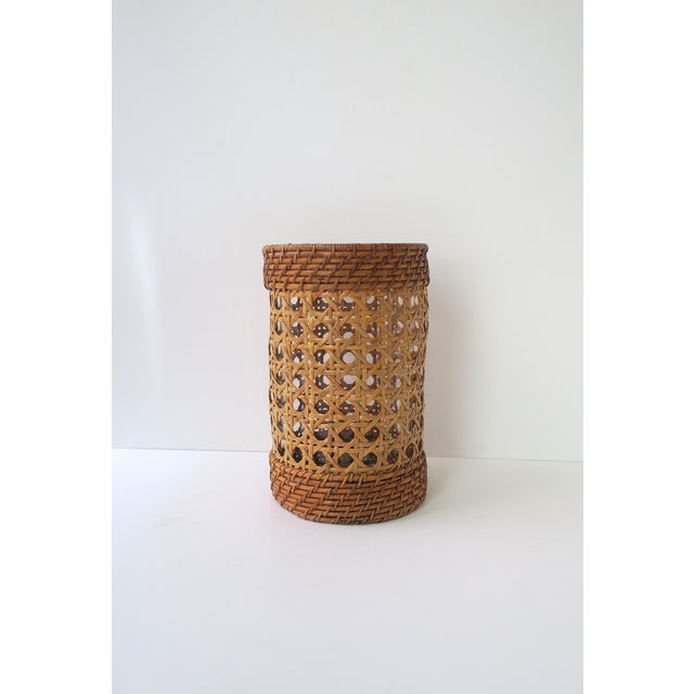 A woven wicker cane and glass hurricane candle table lamp, circa late-20th century. A woven cane and wicker hurricane...
